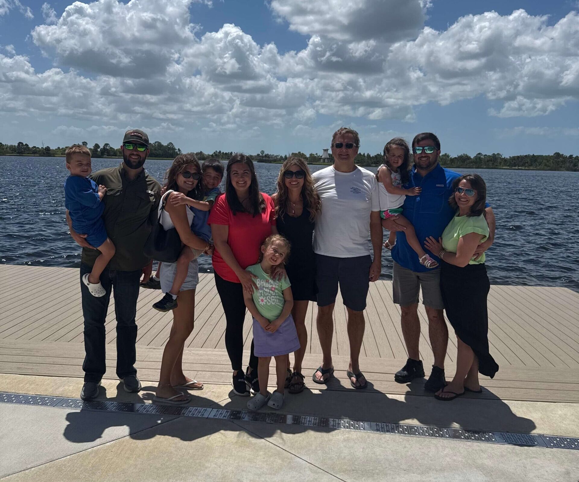 The Walsons family standing as a group on a waterside dock under clouds on a sunny day