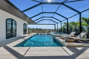 Indoor pool with dark frame and glass roof, surrounded by landscaping