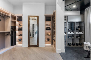 Walk-in closet with light wood shelves and drawers, a large mirror, and a dark ceiling.