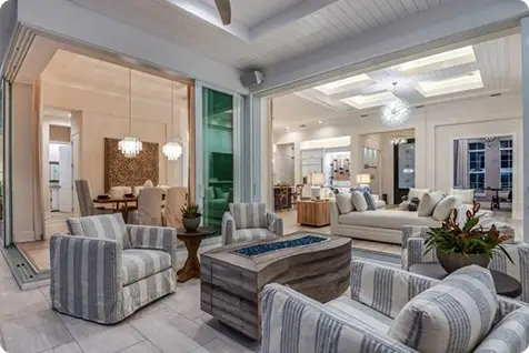 Open-concept interior of a luxury home with lounge seating, indoor-outdoor living area, modern lighting, and elegant furnishings designed for comfort and flow.