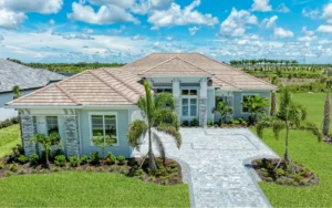 Front exterior of a modern Florida custom built home with large paved driveway, small trees, and manicured lawn