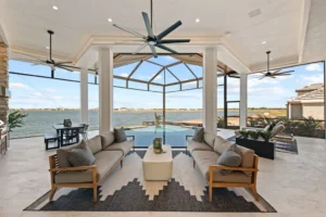 Sarasota luxury home with expansive indoor-outdoor living area, large glass openings, covered seating, swimming pool, and waterfront views.