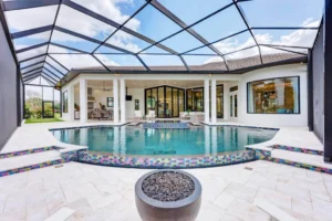Sarasota luxury home with expansive glass doors connecting the interior living space to a covered patio, swimming pool, and outdoor living area.