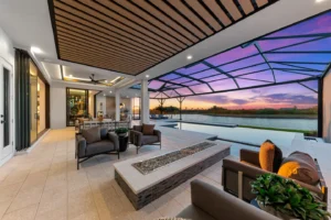 Indoor-outdoor living with a covered lanai, modern lounge seating, and pool views at sunset