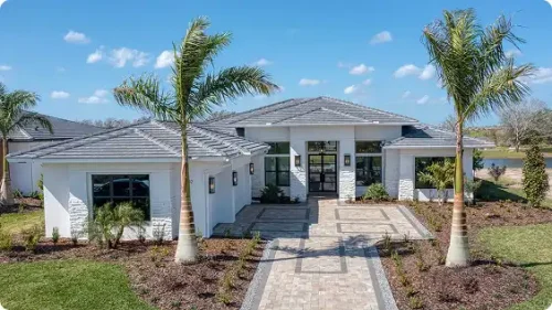 Modern Florida luxury home exterior with palm trees and stone walkway built by a custom home builder.